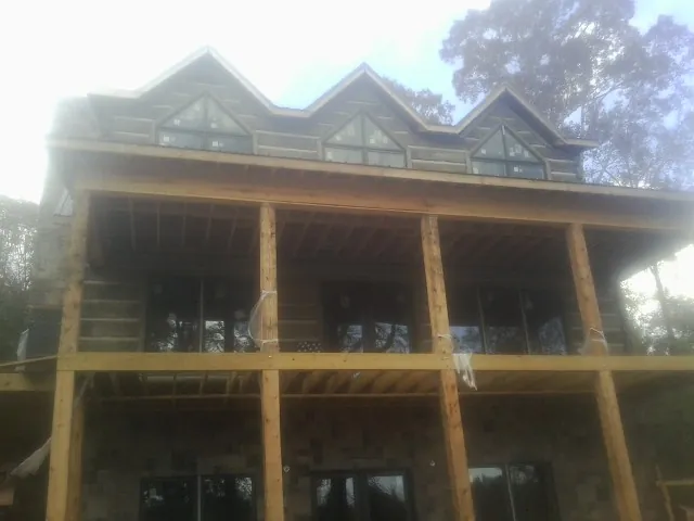 Dormers and porch framing on a large log home under construction — Roof Coating work by our crew in Devers