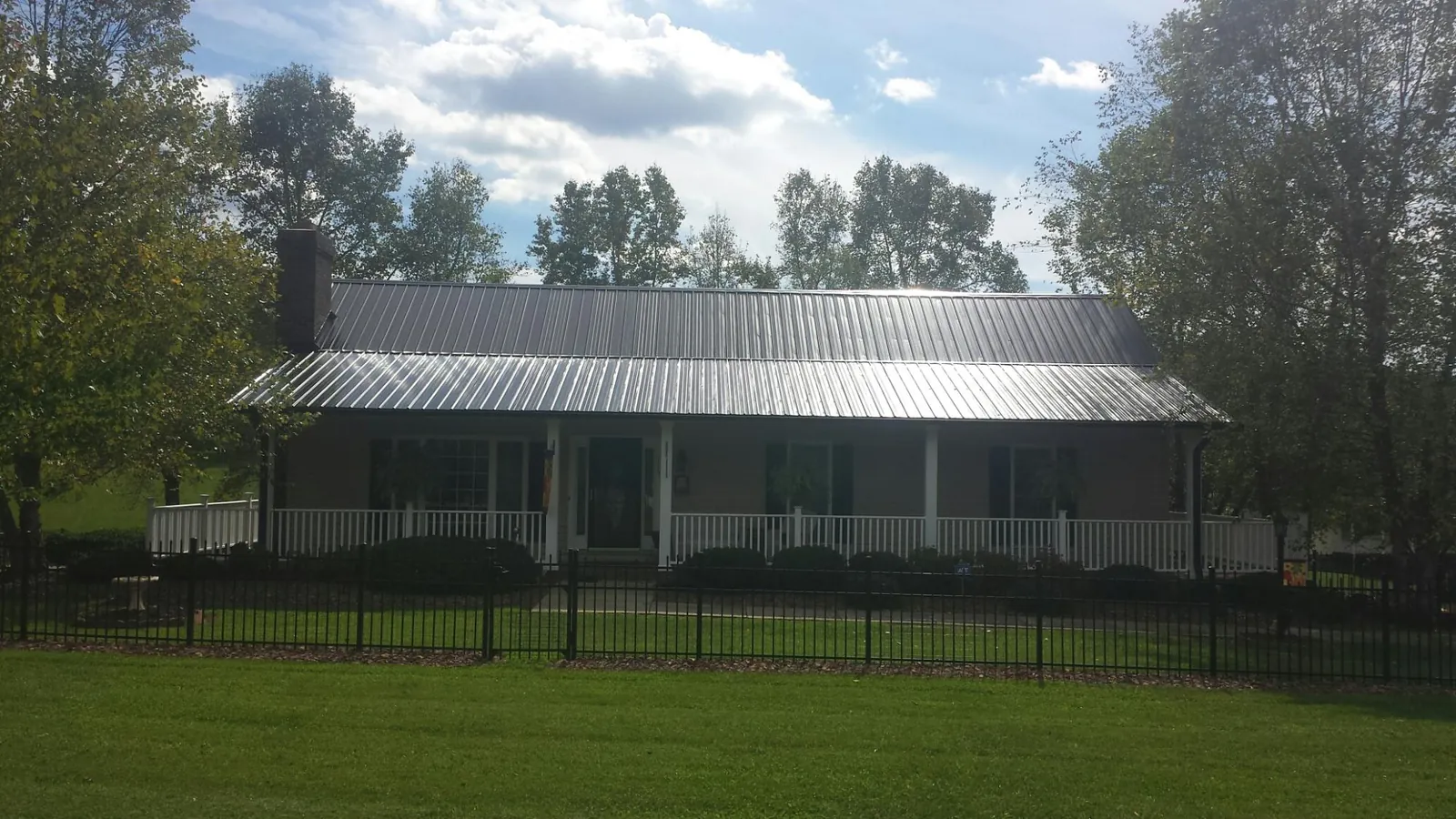 Gray metal roof on a brick ranch with a full width front porch — Gutter Guard Installation work by our crew in Devers